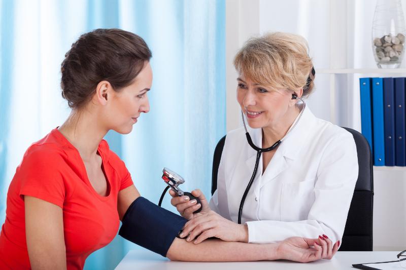 A medical professional performing a pre-employment physical on a patient at an urgent care clinic in Aurora